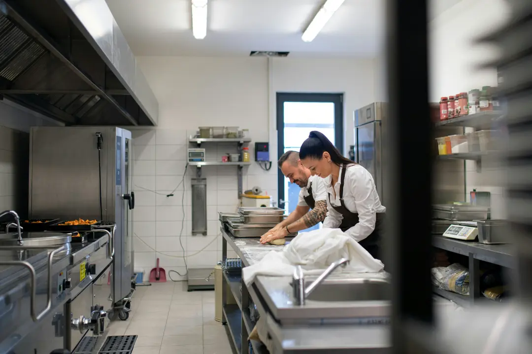 This image shows two chefs, a man and a woman, working together in a professional kitchen.