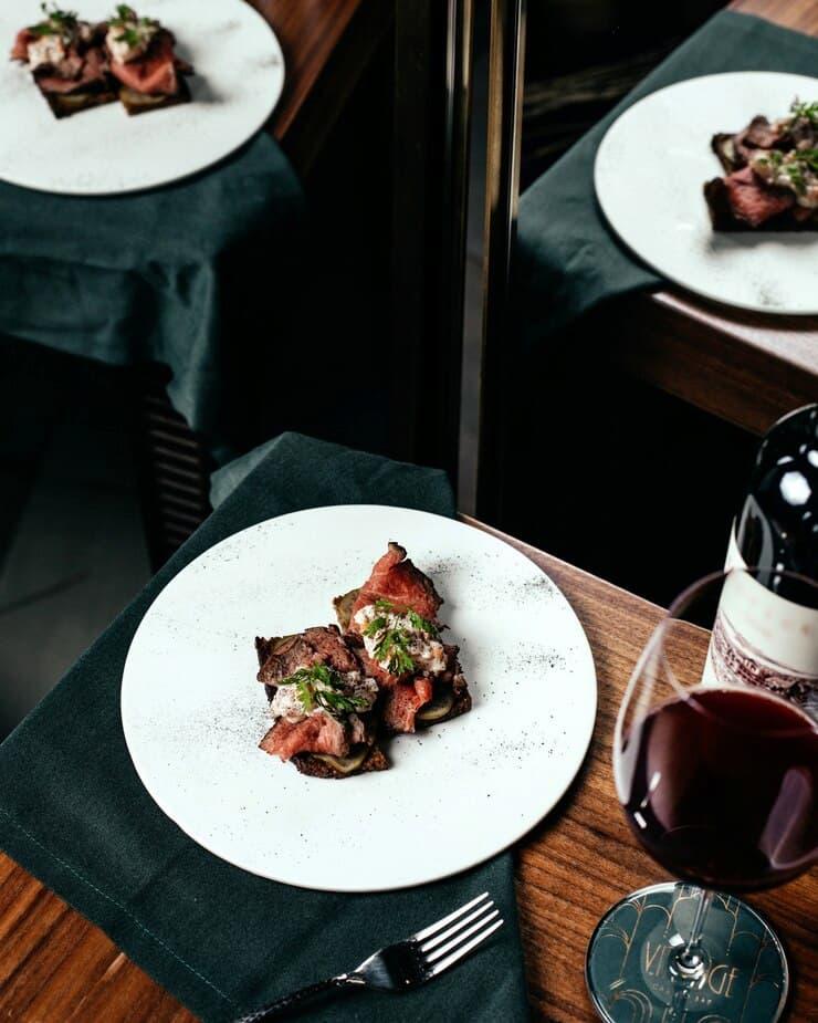 A photograph of a beef dish and a glass of wine.