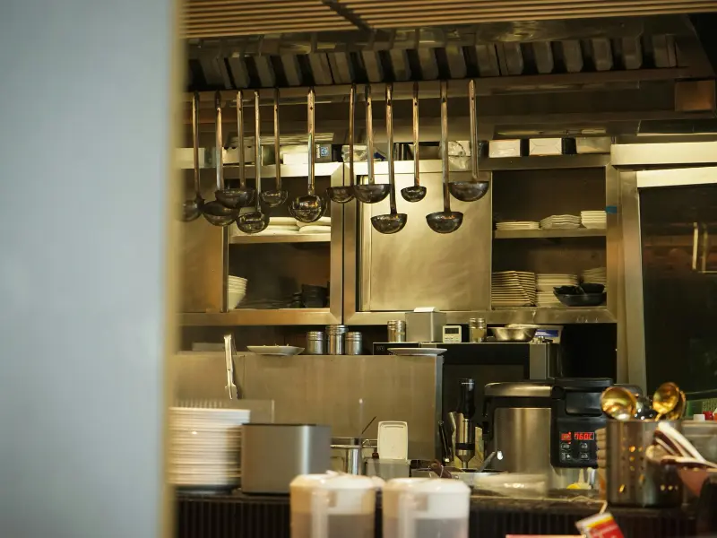 
Here is a description of the image in English:

This is a close-up photograph of a section of a commercial kitchen or the service area of a restaurant. The space is dominated by stainless steel surfaces, which are typical for professional kitchens.