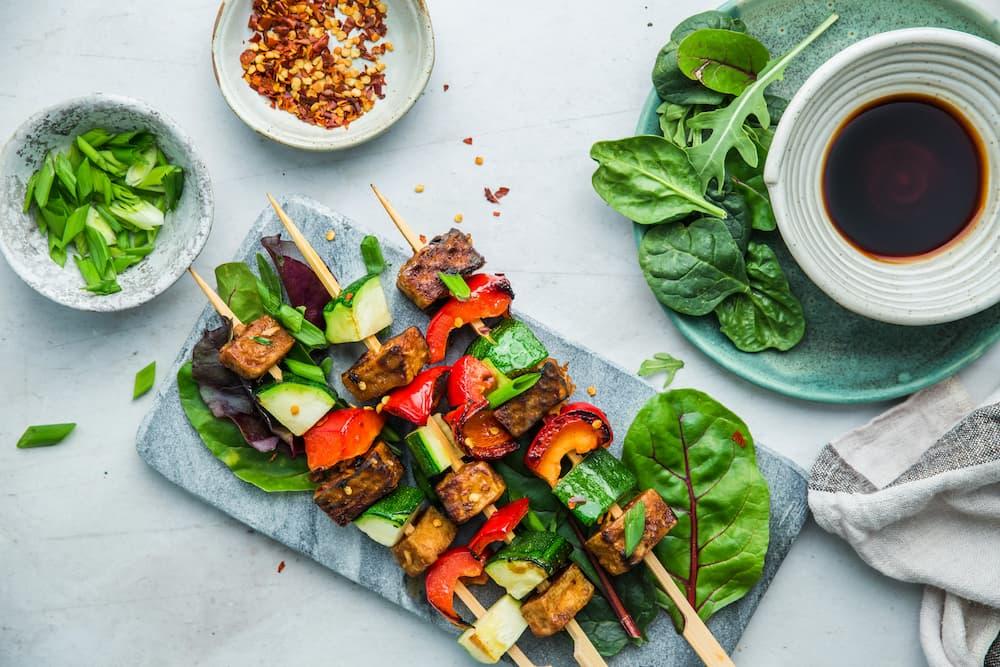 Grilled vegetarian skewers with assorted vegetables, served with sauce and seasonings