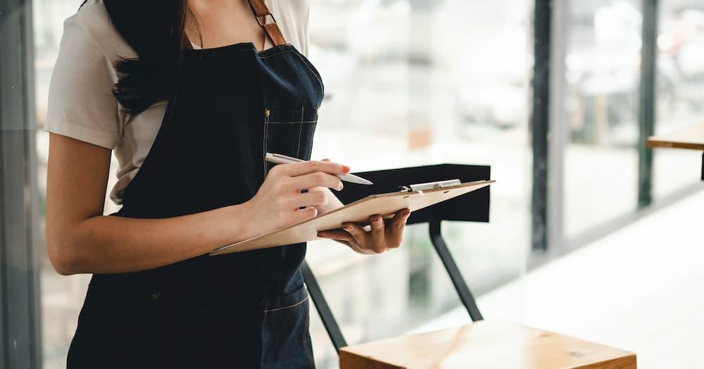 Woman with apron holding a clipboard and pen