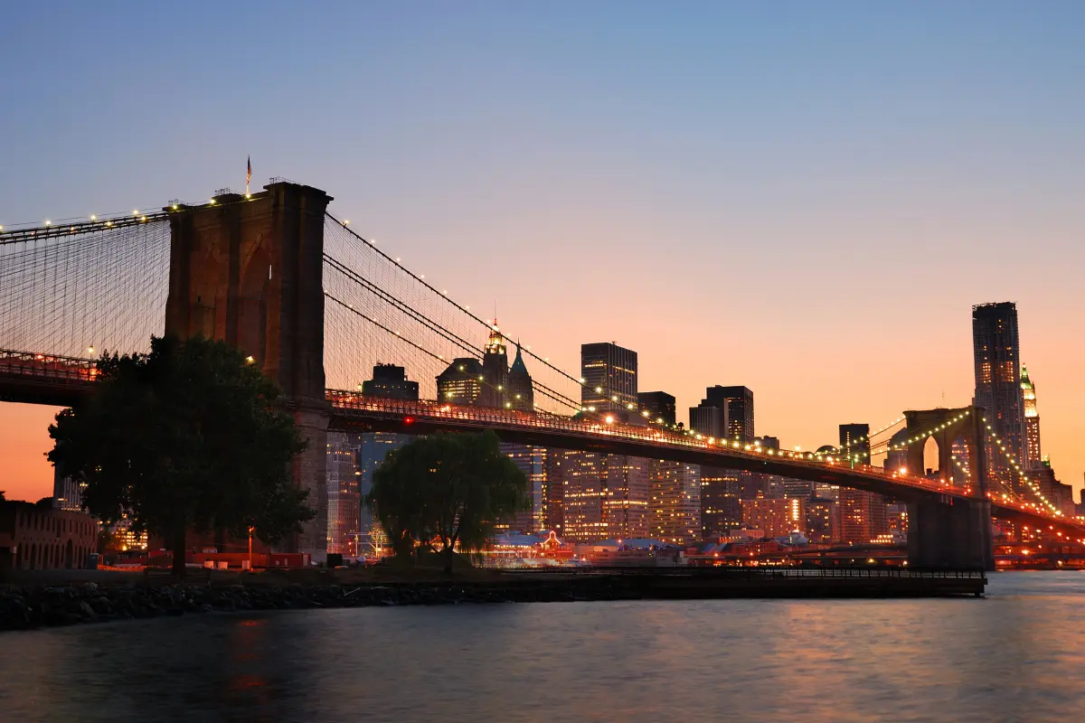 This is a striking photograph of the Brooklyn Bridge in New York City, captured during the period of twilight, known as the "blue hour" or shortly thereafter.