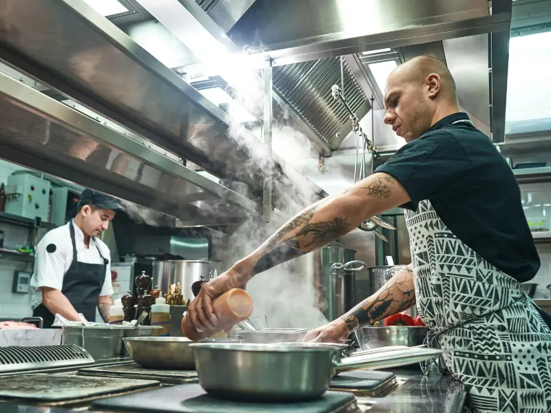 This is a dynamic photograph captured inside a busy, professional kitchen environment.