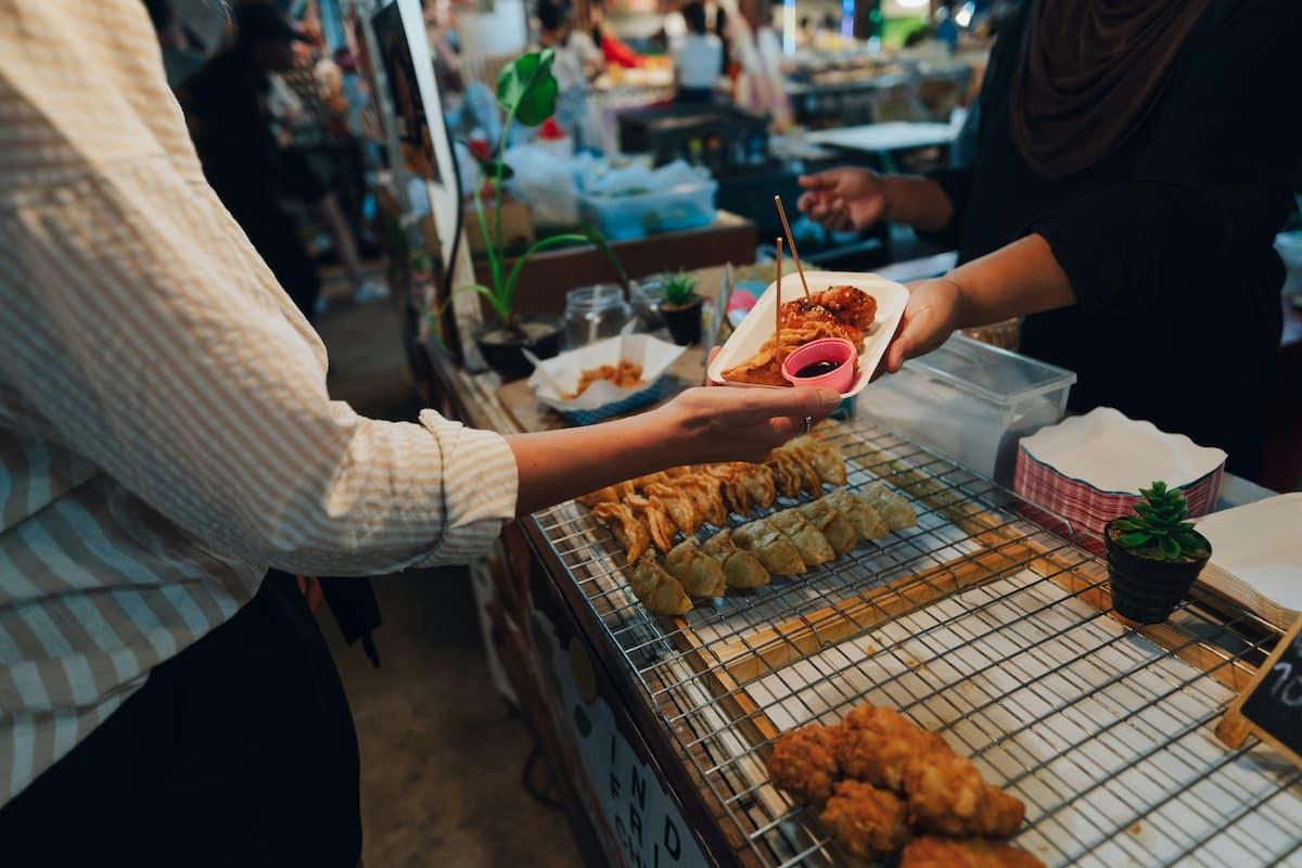 Customer receiving food at a stall during a busy event, illustrating ghost kitchen festival logistics in action.