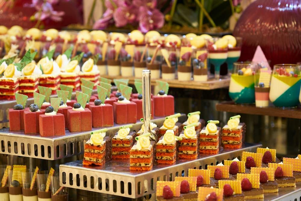 Delicious options of colorful and elaborate desserts at a buffet, including layers of gelatin, creams, and fresh fruits, perfect for a holiday
