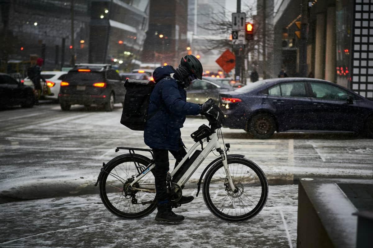 Food courier on a bike braves snowy streets, showing how weather affects food delivery in urban environments.