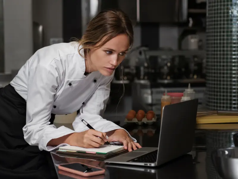 The image shows a female chef or restaurant professional working in a commercial kitchen setting.