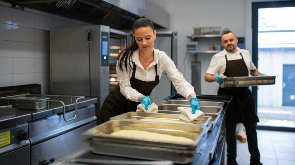 This photo shows a wider perspective of a large commercial kitchen, emphasizing the logistical part of serving many orders.