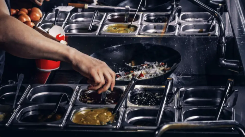 This image captures the fast-paced environment of a professional kitchen, specifically a commercial wok or stir-fry station.