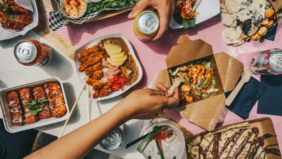The image provided is a vibrant, top-down view (flat lay) of a social gathering centered around diverse street food.