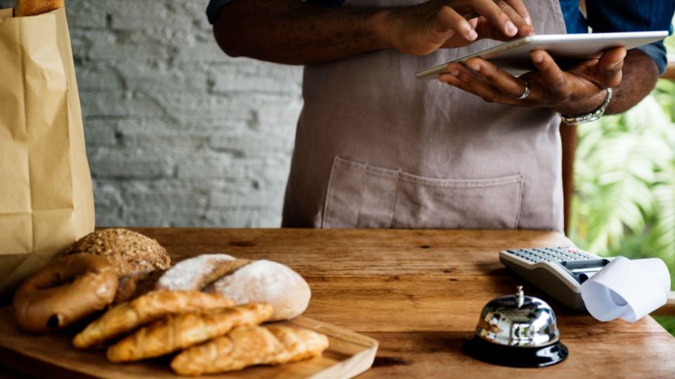 It captures the moment a staff member manages an order using technology at a rustic service counter.