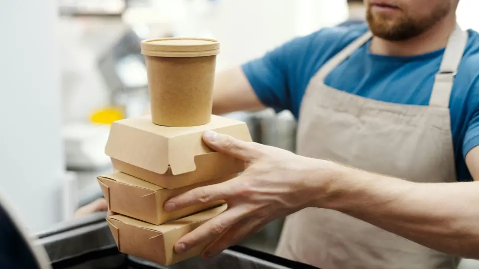 This photo shows a restaurant worker or chef preparing multiple orders for delivery or takeout.