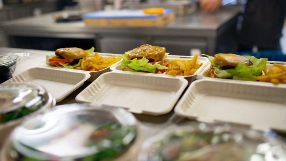 This image captures the final assembly of multiple takeout orders in a clean, professional kitchen setting.