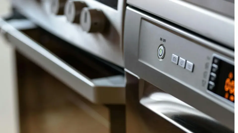 The image shows a close-up view of a modern stainless-steel kitchen appliance, likely a built-in oven or dishwasher. The focus is on the control panel and handle.