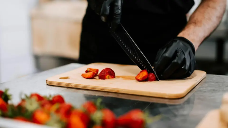 This image captures a close-up, action-oriented moment of food preparation in a professional kitchen.