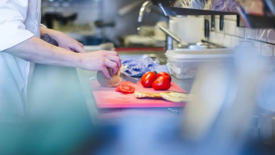 This image captures a chef's hands during the preparation of fresh vegetables.