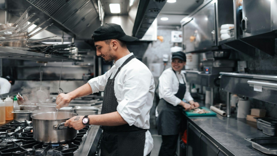 This image captures the vibrant and cooperative atmosphere of a busy professional kitchen during food service.