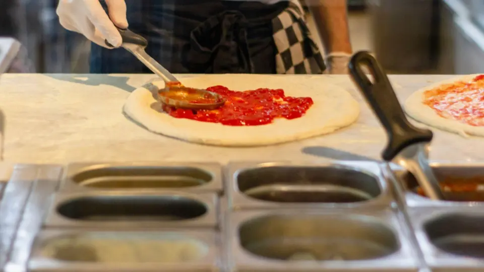 This close-up shot captures the precise moment of assembling a classic pizza.