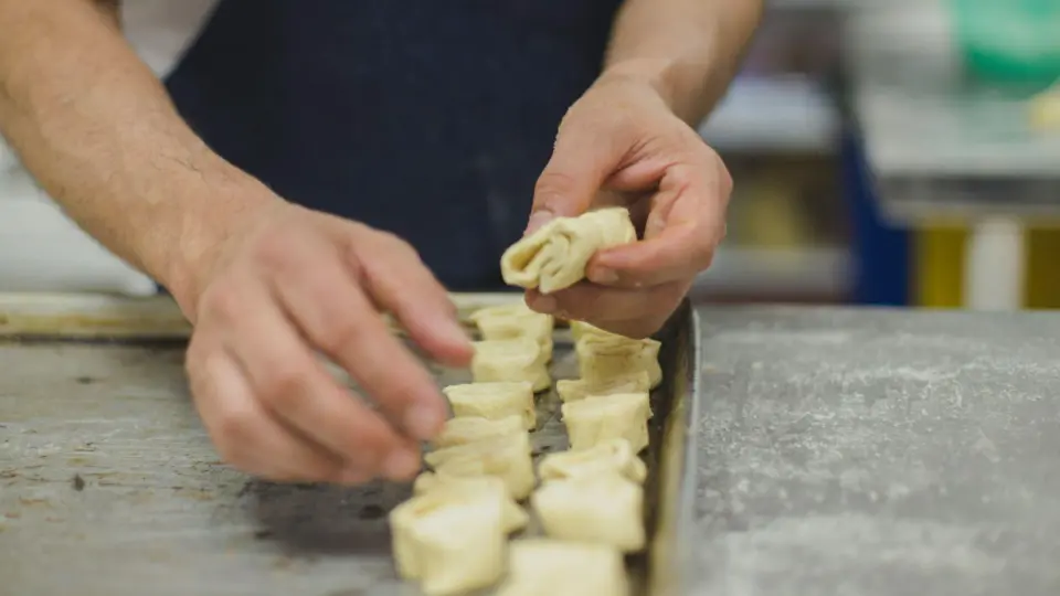 This close-up focuses on the delicate hands-on work of a baker or pastry chef.