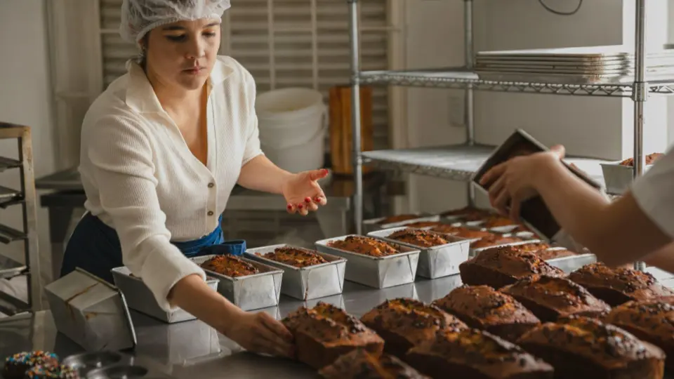 A baker managing a large batch of freshly baked loaves.