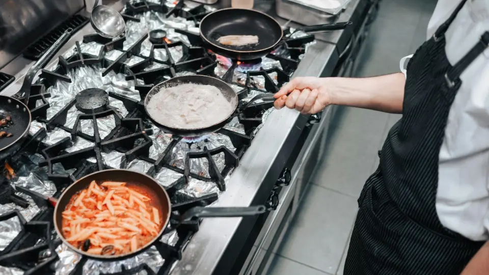 This image captures the intense and dynamic atmosphere of high-heat cooking in a professional kitchen.