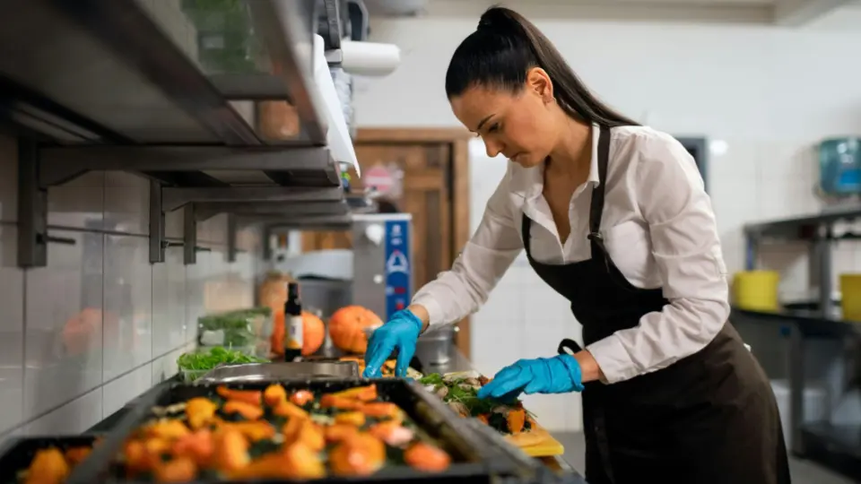 This image captures a close-up, action-oriented view of a chef working at a high-end commercial cooking station.