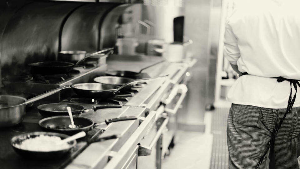 This image provides a close-up, action-oriented view of a chef working at a high-end commercial cooking station.