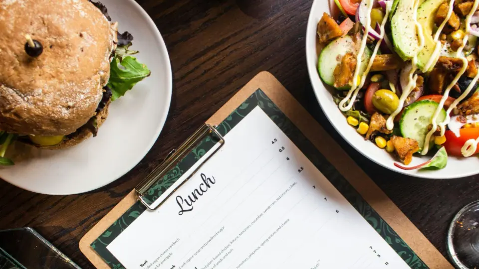 The composition is centered around a printed menu, flanked by two delicious main courses.