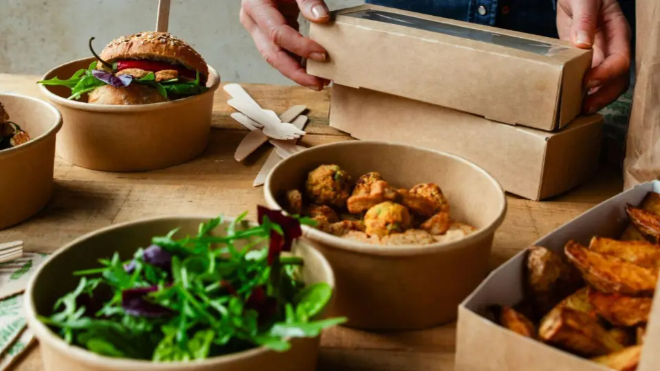 This image displays an assortment of packaged take-out meals, emphasizing eco-friendly presentation.