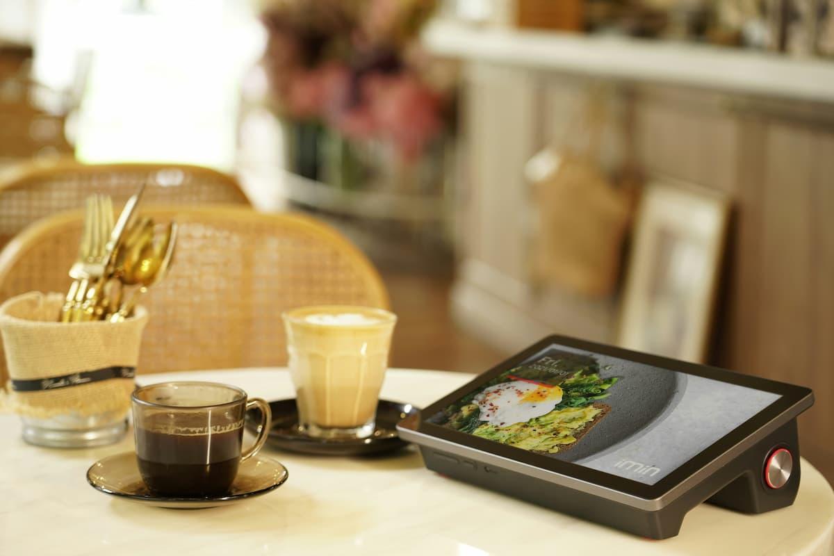 Table with coffee, cutlery, and digital menu display showing AI in restaurants technology in use.