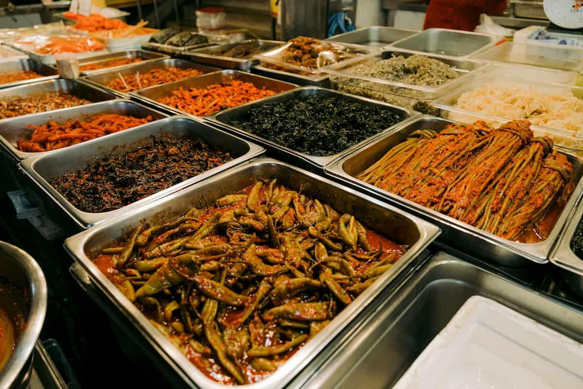 Various trays filled with prepared dishes in a commercial kitchen, highlighting bulk food production for businesses.