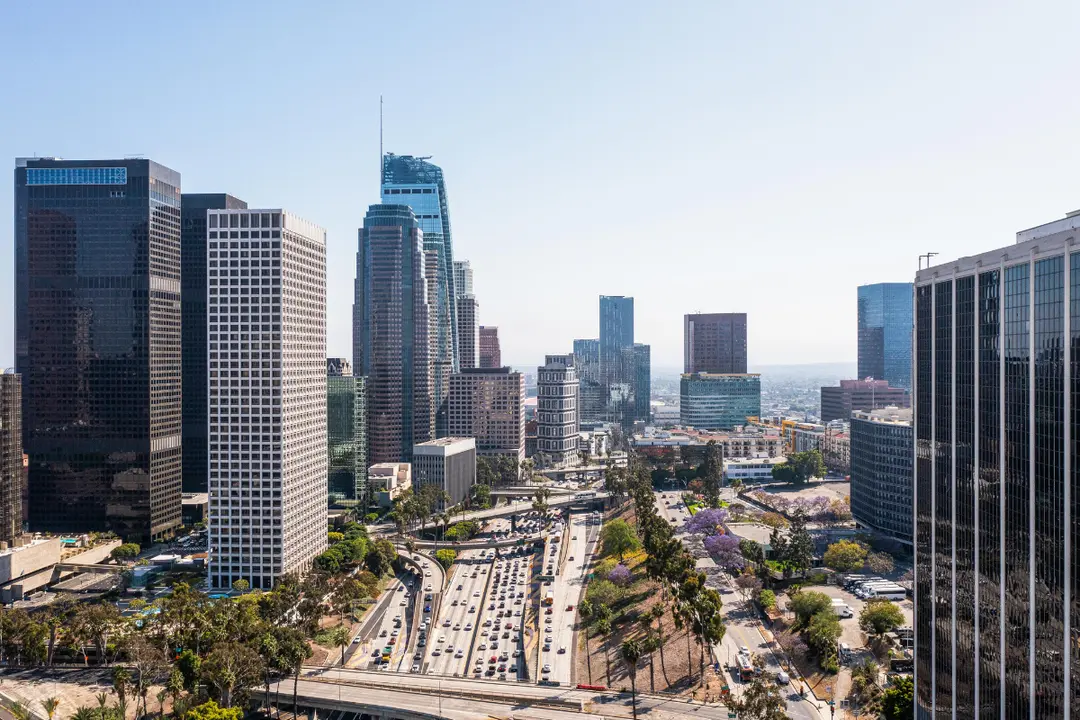This is an elevated, panoramic view of the Downtown Los Angeles (DTLA) skyline in California, USA, on a clear, sunny day.