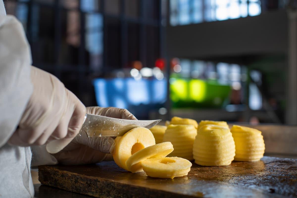 Worker slicing peeled apples in a ghost kitchen setup guide for small batch production environment.