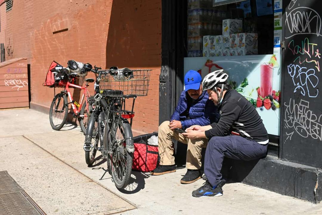 Food delivery workers resting with bikes in NYC, showing how ghost kitchens can help New York restaurants boost delivery services.
