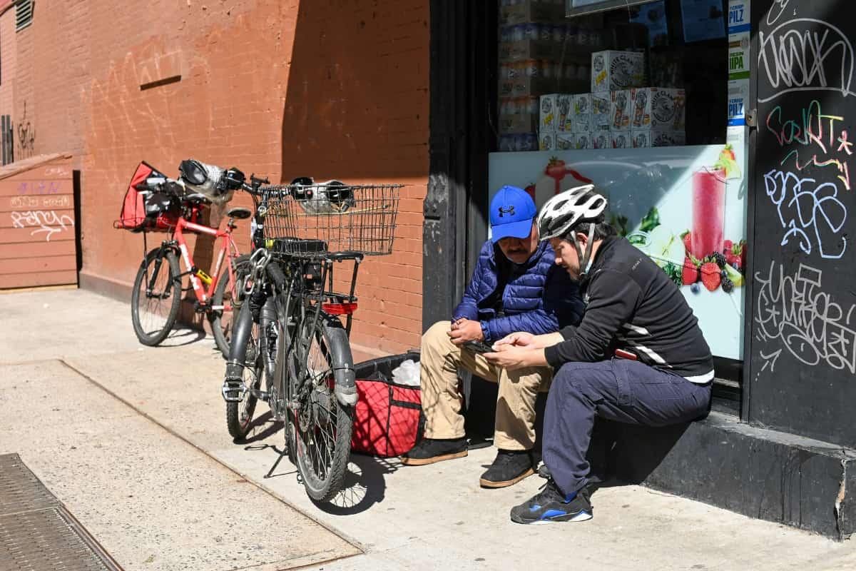 Food delivery workers resting with bikes in NYC, showing how ghost kitchens can help New York restaurants boost delivery services.