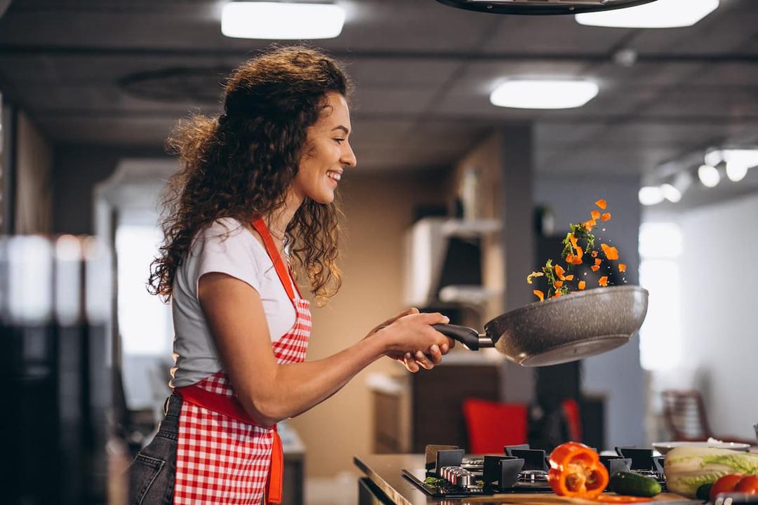 Woman cooking in a modern kitchen; vibrant and professional setup showing how to choose a private label kitchen effectively.