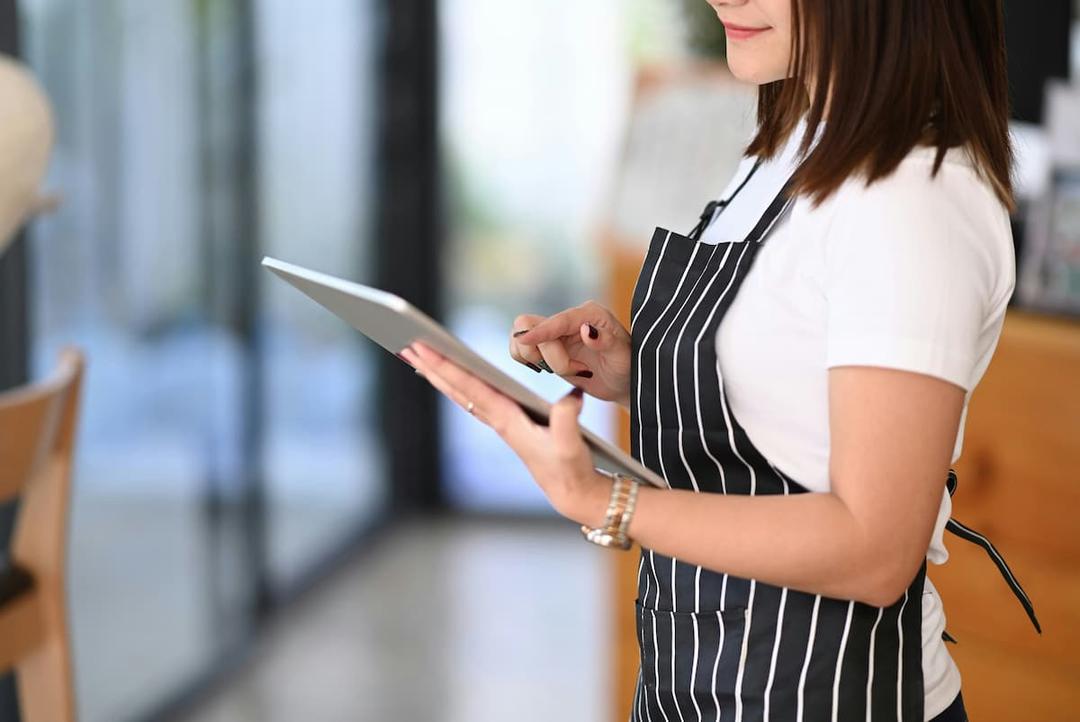Staff member uses tablet, showing how to integrate POS systems and online platforms for production kitchens efficiently.