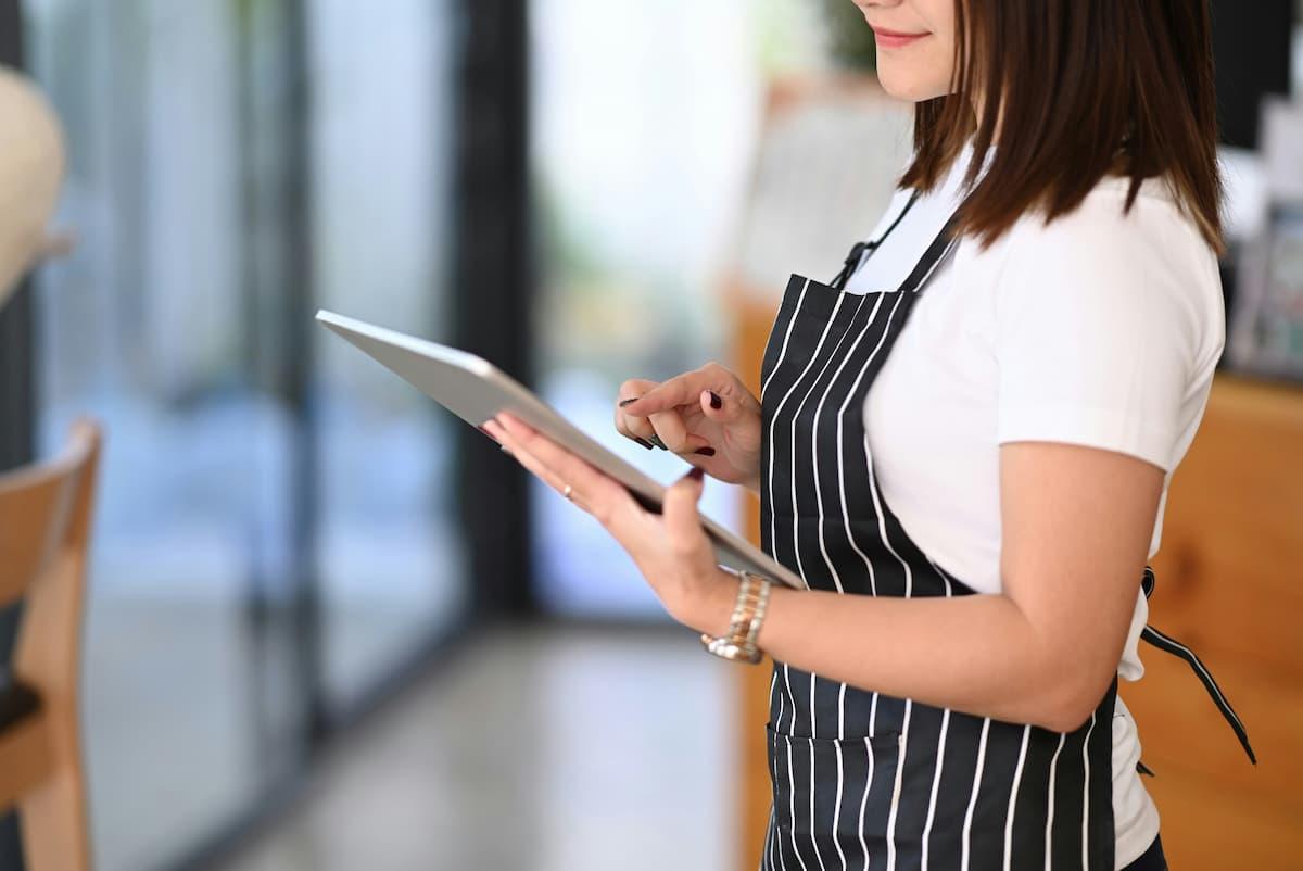 Staff member uses tablet, showing how to integrate POS systems and online platforms for production kitchens efficiently.