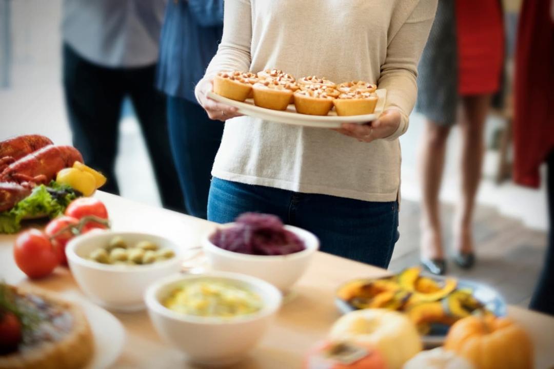 Person serving cupcakes at a buffet, showing how to manage food production for Independence Day gatherings efficiently.