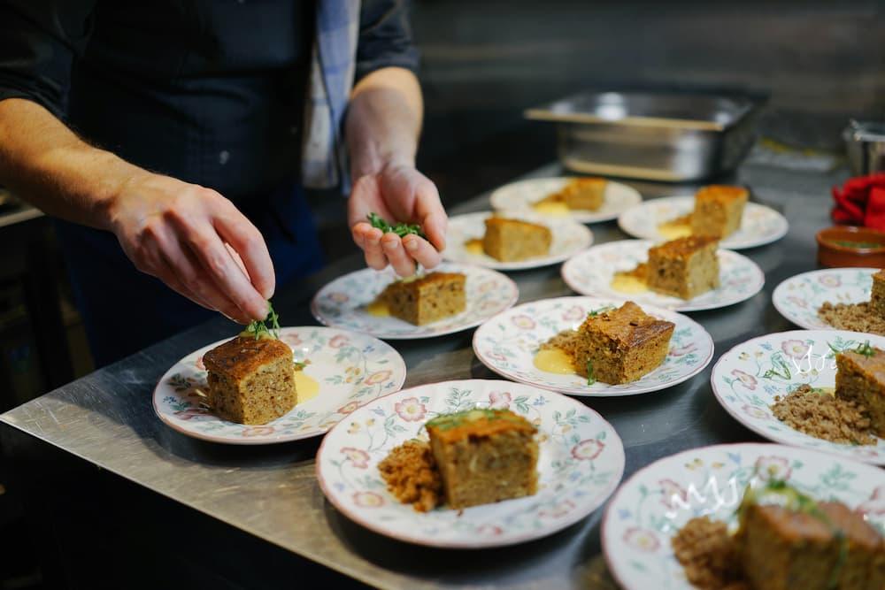 A chef finishing dishes with delicious layers of cake, garnishing with fresh herbs