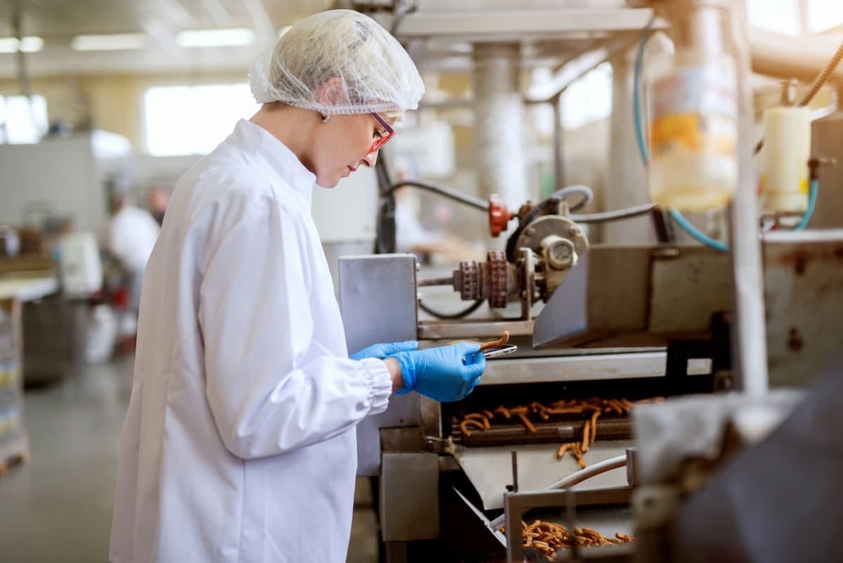 Worker inspects snack products to ensure nutritional integrity in food manufacturing at a modern production facility.