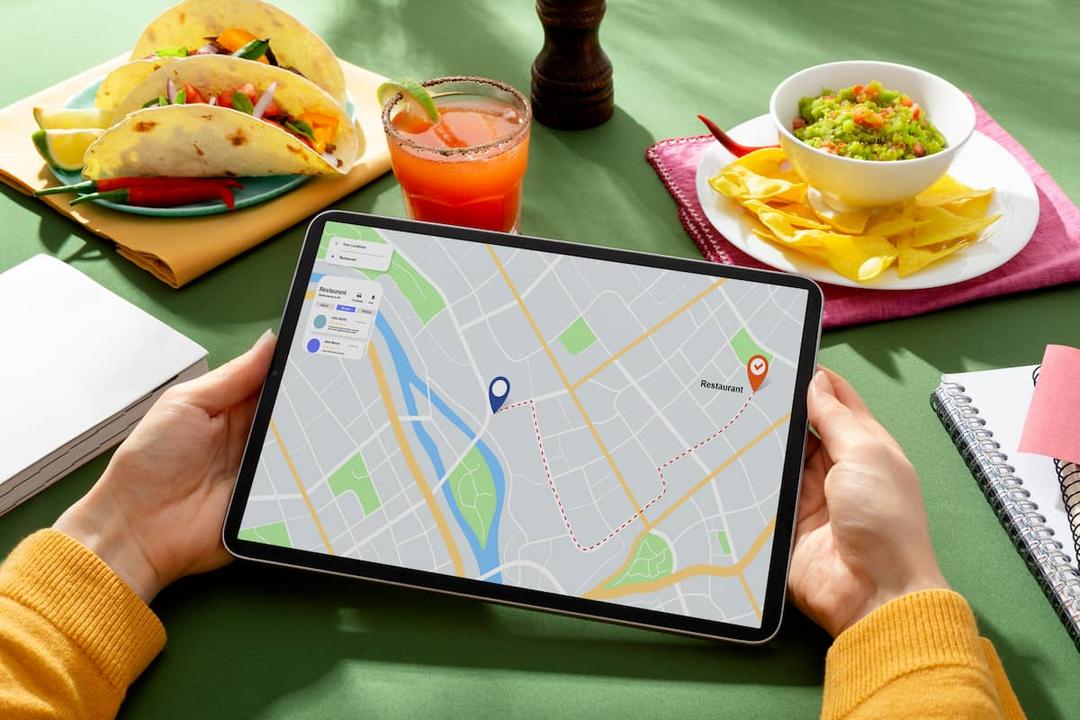 Person holding tablet with a map and route, illustrating restaurant location strategy for food delivery.