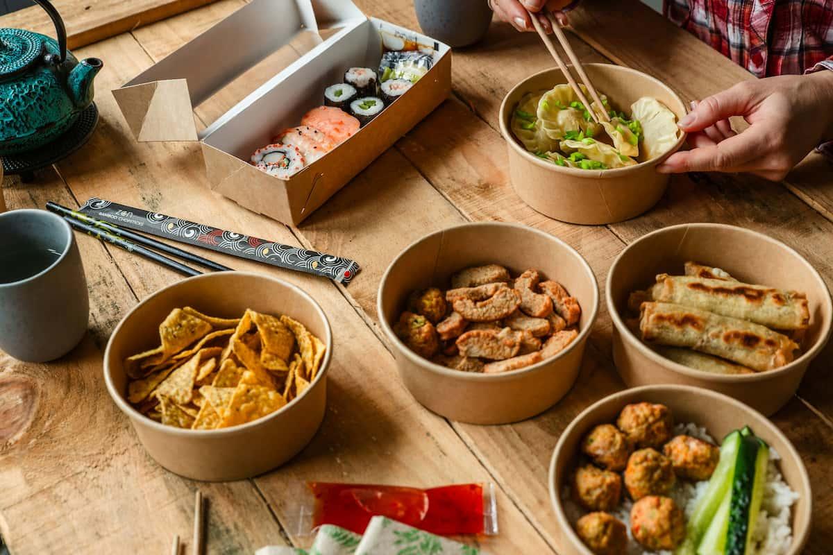 Wooden table with assorted takeout meals, perfect for scaling a food business with co packing kitchens.