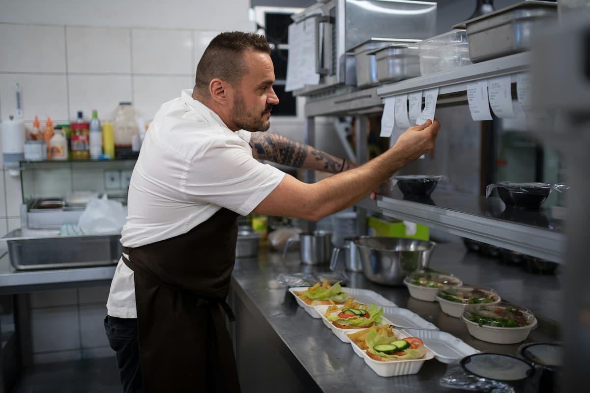 Chef organizing orders in a professional kitchen, illustrating the efficiency debate of shared vs private kitchens.