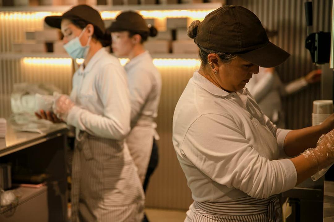 Employees in uniform working in a kitchen during a hands-on session focused on training for kitchen staff.