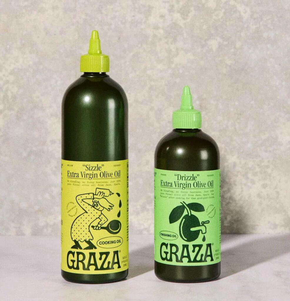 Unique food packing featuring two bottles of Graza Extra Virgin Olive Oil. One bottle is labeled 'Sizzle' Cooking Oil with a vibrant yellow label and a cartoon chef illustration, while the other is labeled 'Drizzle' Finishing Oil with a green label and an olive illustration. Both bottles are designed with green caps, highlighting their stylish and functional packaging.